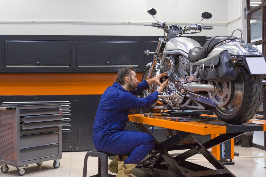 A mechanic conducting maintenance on a motorcycle in a garage